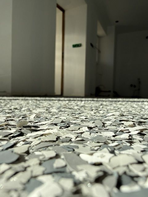 Gros plan d'un sol en résine à paillettes (flakes) gris et blanc — réalisation ALR Design