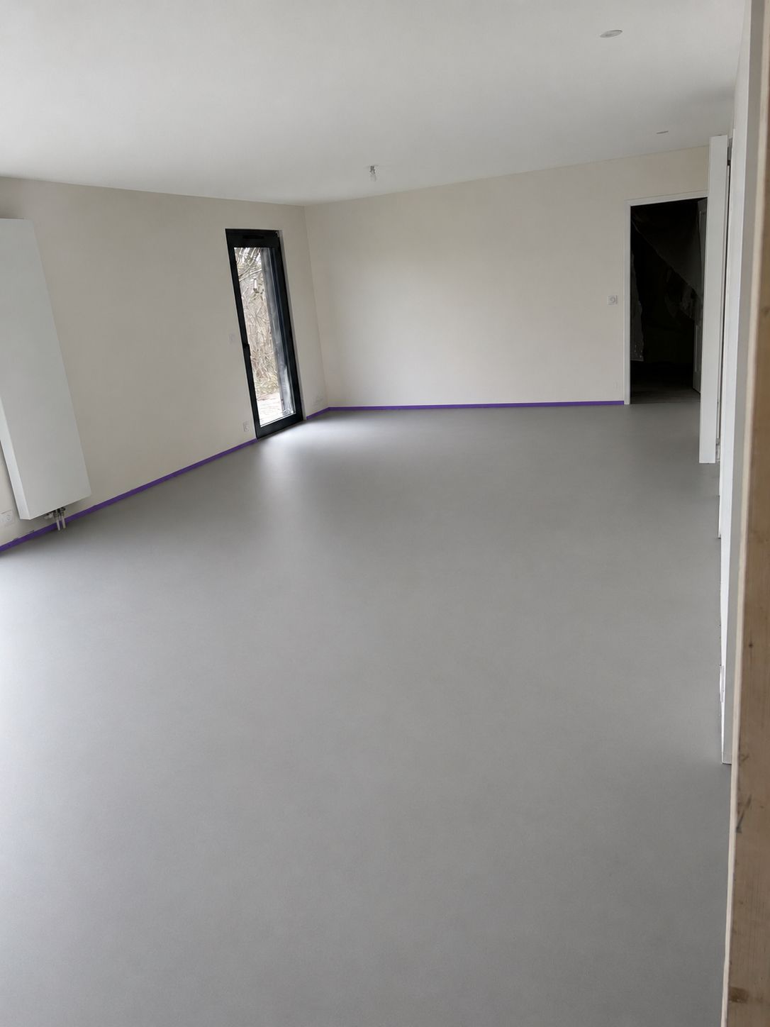 Sol en résine monochrome gris satiné dans une pièce à vivre — réalisation ALR Design à Tignes
